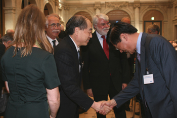 Prof.Tatsumi receiving congratulations from commissioner Kobayashi